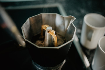 Preparing fresh coffee in moka pot on electric stove. Opening the lid to see if coffee is ready.