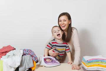 Little boy, woman ironing family clothing on ironing board with iron. Son help mother with...