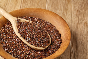 Wooden spoon with flax seeds on rustic background, top view, close-up, shallow depth of field, selective focus