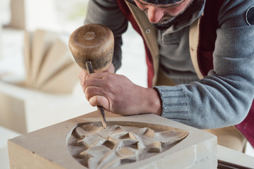 Stonemason chiseling on floral stone pattern