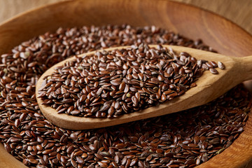 Wooden spoon with flax seeds on rustic background, top view, close-up, shallow depth of field, selective focus