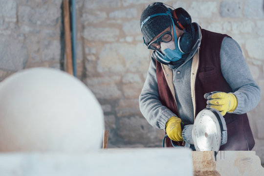 Steinmetz arbeitet mit Schutzkleidung in der Werkstatt