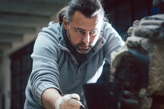 Restaurator pr&uuml;ft in voller Konzentration ein zu erhaltendes Werk