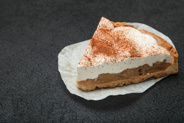 Homemade organic pie with apples and cinnamon on a black table.