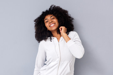 cheerful young black girl standing against gray wall