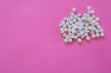 Large amount of white pills isolated on pink background with space for add text. Colorful pop photography, concept of medicine and human health.