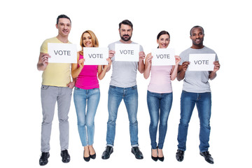 Naklejka premium Influencing the crowd. Good-looking alert athletic young men and women wearing casual clothes and smiling and holding tables and asking to vote