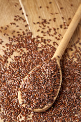 Wooden spoon with flax seeds on rustic background, top view, close-up, shallow depth of field, selective focus
