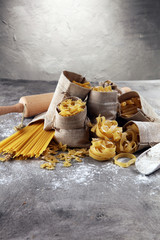 Various mix of pasta on grey rustic background. Diet and food concept.
