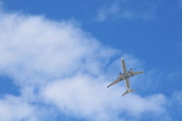 Fototapeta na wymiar Passenger airplane flying under cloudy blue sky