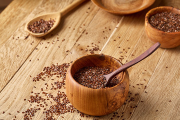 Wooden spoon with flax seeds on rustic background, top view, close-up, shallow depth of field, selective focus