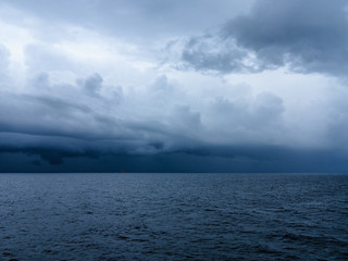 Dark blue sky and dark blue sea color and storm raining cloud background.