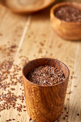 An overturned wooden bowl with linseeds on a rustic background, close-up, shallow depth of field, selective focus