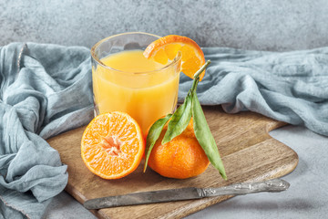 Fresh orange tangerines with green leaves and juice glass - 193993302