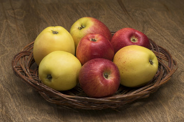 apples in a wicker plate on a wooden table