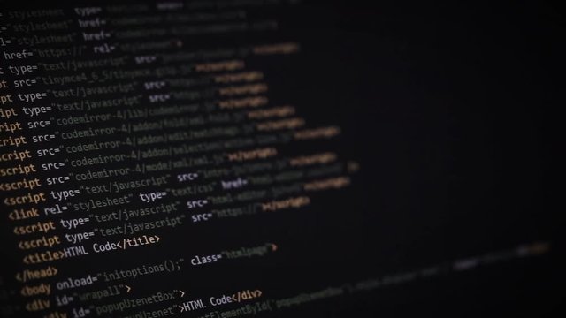 Website development. Closeup of HTML, CSS, JavaScript and PHP colorful code scrolling over dark background on computer screen