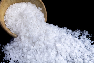 Sea salt white crystals in wooden bowl isolated on the gray background.