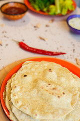 Fresh unleavened cakes on the background of plates with greens
