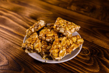 Ceramic plate with peanut brittles on wooden table.