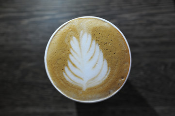 A cup of fragrant and beautiful coffee is on the table. Picture on foam - leaf