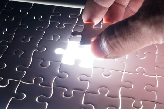 Male or Man Hand and Finger put Piece of Jigsaw in Place to Solve or Match Puzzle