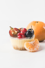 close up view of sweet cupcake with berries and fruits isolated on white