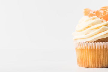 close up view of sweet cupcake with cream and tangerine isolated on white