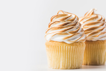 close up view of sweet cupcakes with meringue isolated on white