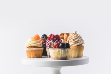 close up view of various sweet cupcakes on cake stand isolated on white - obrazy, fototapety, plakaty
