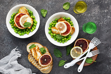 Green young peas, cheese haloumi, lemon. orange salad with slices of bread. Top View