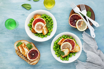 Green young peas, cheese haloumi, lemon. orange salad with slices of bread. Top View