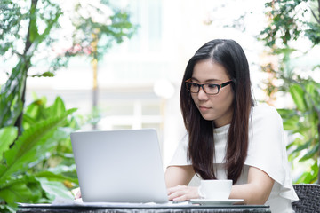 Beautiful asian attractive woman has working and typing on laptop computer for business marketing at coffee cafe in the morning with happy and relaxing time.