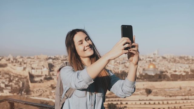 Pretty girl takes selfie in Jerusalem old town. Cute local girl smiles happy, taking photos. Ancient Israel panorama 4K.