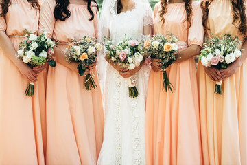 Four girlfriends and a bride hold beautiful wedding bouquets in their hands