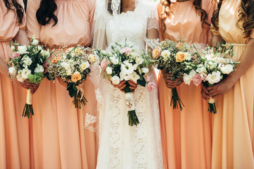 Four girlfriends and a bride hold beautiful wedding bouquets in their hands