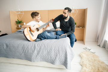 Father and son having fun while play the guitar