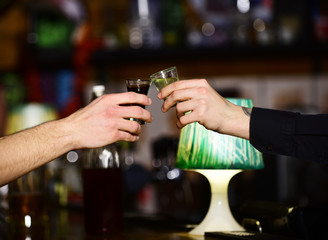 Male hands cheer with alcohol on blurred bar background.