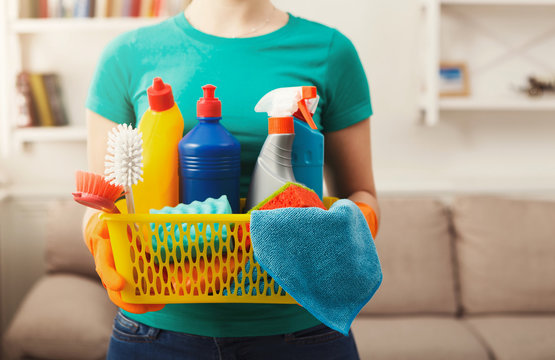 Young woman holding bucket with cleaning items, close up