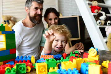 Obraz premium Young family spends time in playroom. Parents watch son