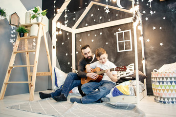 Father showing chords on guitar to his son