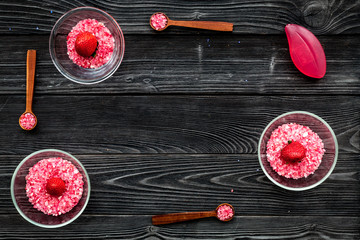 Aromatheraphy in spa. Strawberry pink spa salt in bowls on black wooden background top view copy space