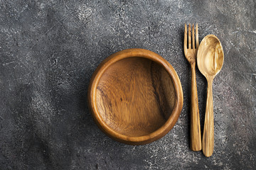 Wooden plate, spoon, fork on a gray background. Top View.