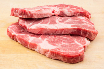 Raw pork neck three meat cuts isolated on wood background fresh slices without bone .