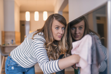 Beautiful young smiling woman cleaning house with microfiber cloth. Selective focus on hand.