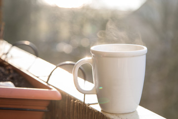Dampfender Kaffee Becher am Morgen auf Balkon