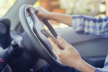 
close up on businessman hand holding and using smartphone in car while driving on the road for heading to destination , transportation and technology concept