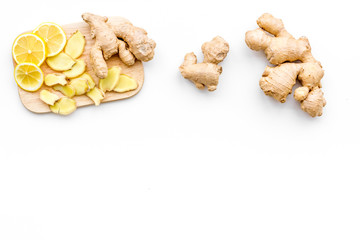 Fresh ginger root and lemon slices pattern on cutting board on white background top view copy space