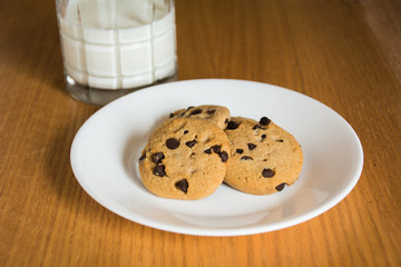 A glass of milk with chocolate chip cookies.