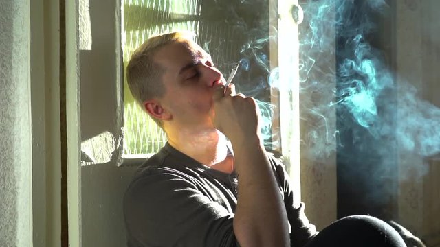 A man smokes a cigarette at home