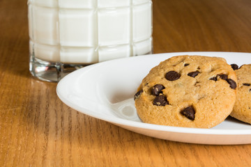 A glass of mild with chocolate chip cookies.